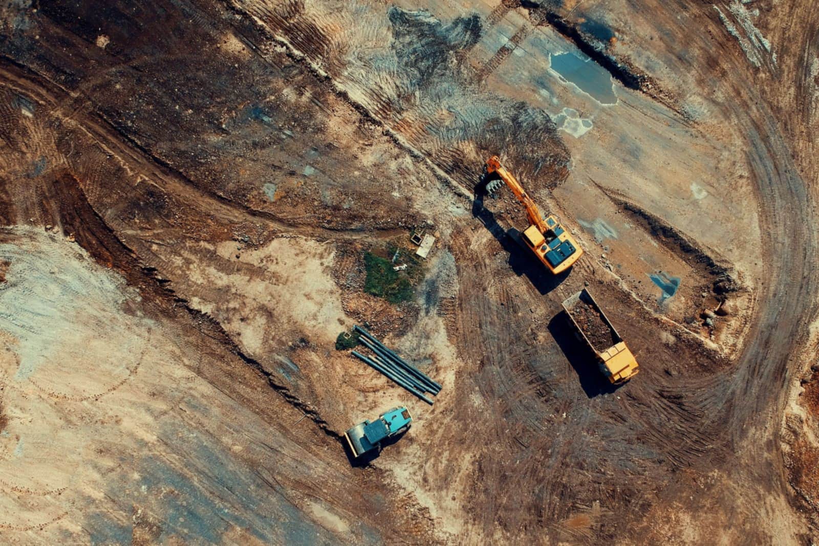Aerial view of an excavator loading earth into a dump truck on an earthworks site.