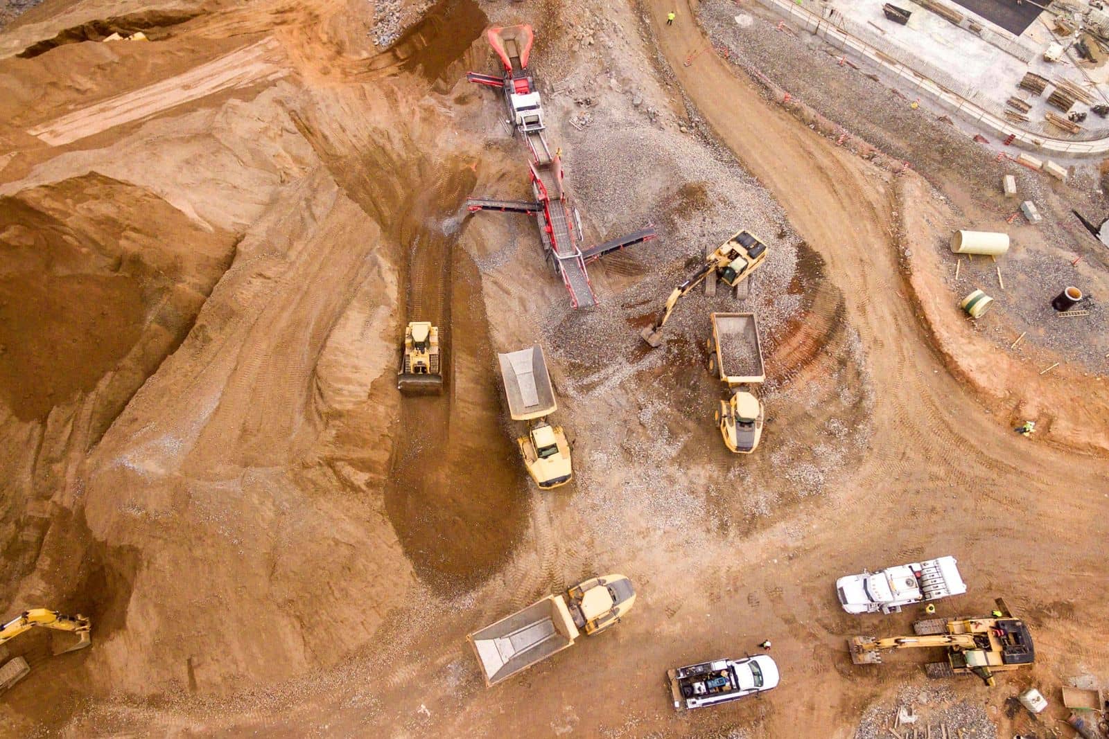 Aerial view of a large site where excavators, a dozer, haul trucks and service pickups work at the same time.